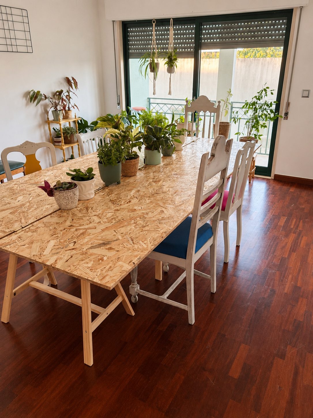 Mesa comprida em OSB com plantas, junto a uma janela grande com luz de fim de tarde